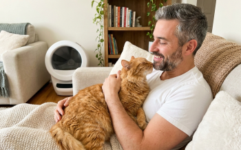 Man with his cat with a Litter Robot in the background